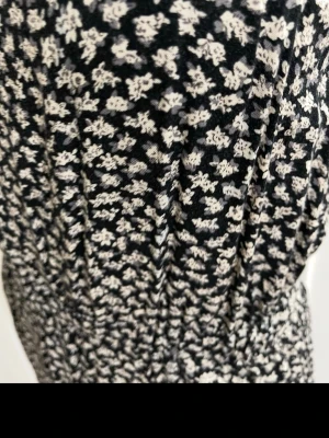 Svart jumpsuit med småblommigt mönster - Snygg svart jumpsuit med vitt småblommigt mönster och resår i midjan. Lätt och luftig modell som sitter bekvämt. Perfekt för dig som gillar en avslappnad men trendig stil. Materialet känns mjukt och följsamt mot huden.