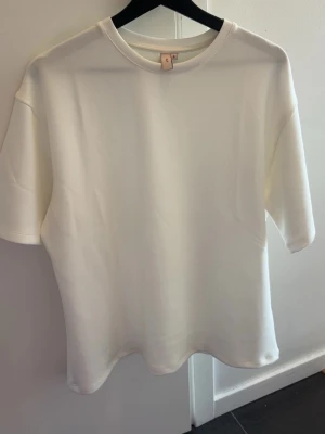 Vit basic t-shirt i bomull - Enkel och stilren over size vit t-shirt med rund halsringning och korta ärmar. Tillverkad i mjuk bomull, perfekt för en clean och avslappnad look. Passar till allt och är ett måste i garderoben.