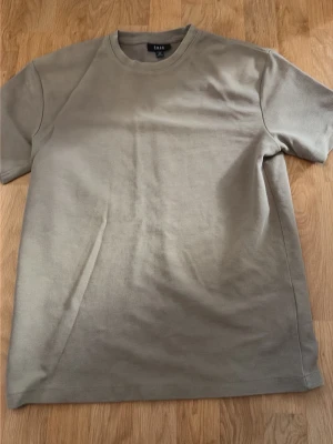 Beige basic t-shirt från Asos - En stilren beige t-shirt från Asos med rund hals och korta ärmar. Tillverkad i mjuk bomull som känns skön mot huden. Perfekt att matcha med jeans eller shorts för en clean och enkel look. Perfekt inför sommaren!
