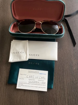 Äkta Gucci solglasögon - Säljer ett par Gucci solglasögon i mycket bra skick. Köptes på Careofcarl för många år sedan men då jag har andra som jag använder mer så är dom använda väldigt sparsamt.  Cond: 10/10 Dustbag, fodral, microfiberduk ingår.  Modellen heter GG0058SK och den verkar inte tillverkas längre. Bevis för äkthet finns!