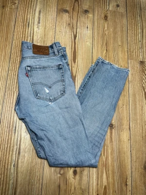 Levi's ljusblå raka jeans - Säljer ett par klassiska ljusblå Levi's jeans med rak passform och hög midja. Jeansen har fem fickor, slitna detaljer och den ikoniska röda Levi's-lappen på bakfickan. Tillverkade i bomull för en skön vintagekänsla.