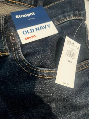 Mörkblå straight jeans Old Navy - Snygga mörkblå jeans från Old Navy i straight fit-modell. Klassisk femficksdesign med kontrastsömmar och lätt slitning framtill. Perfekta för en avslappnad och stilren look. Tillverkade i denim med en bekväm passform. 2st en mörkblå och en svart. Köpta i USA. Pris per st!