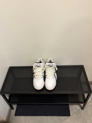 Nike Air Flight vita sneakers - Säljer ett par vita Nike Air Flight sneakers med röda och svarta detaljer. Skorna har klassisk hög design, tydlig logga på tungan och hälen samt vita snören. Perfekt för dig som gillar retrostil och streetwear.