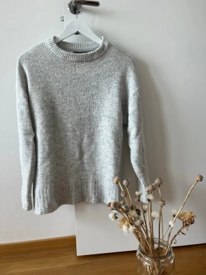 Ljusgrå stickad tröja från Amisu - Mysig ljusgrå stickad tröja från Amisu med rund halsringning och ribbade muddar. Perfekt för lager-på-lager och enkel att matcha med olika outfits. Tröjan har en klassisk rak passform och är tillverkad i mjukt material.