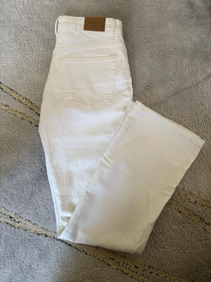 Vita raka jeans från Gina Tricot - Säljer ett par vita raka jeans från Gina Tricot. Klassisk femficksmodell med dragkedja och knapp framtill. Jeansen är i bomull och har en stilren look som passar till allt. Perfekta för dig som vill ha ett par ljusa jeans i garderoben!