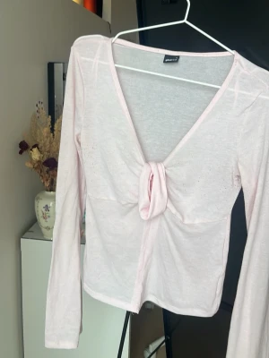 Ljusrosa långärmad knytblus - Säljer en ljusrosa långärmad blus från Gina Tricot med v-ringning och knyt framtill. Tunn och luftig i materialet, perfekt för lager på lager eller som den är. Enkel men ändå stylish detalj med knytet framtill.