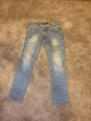 Replay anbass  - Snygga blå Replay anbass med en klassisk femficksdesign. Jeansen har ljusa tvättade partier och Replay-logga på myntfickan. Perfekta för en avslappnad och trendig look. Tillverkade i mjukt denimtyg.