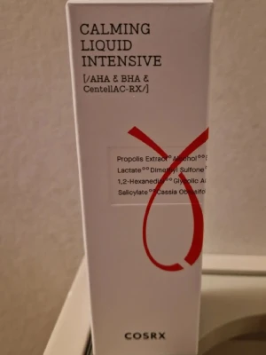 COSRX Calming Liquid Intensive toner - En vit förpackning med röd detalj innehållande COSRX Calming Liquid Intensive toner. Tonern har AHA, BHA och CentellAC-RX, och är framtagen för att lugna huden. Passar dig som vill ha en effektiv och mild toner med ingredienser som propolisextrakt och glykolsyra. Obs datumet går ut 19 mars 2026