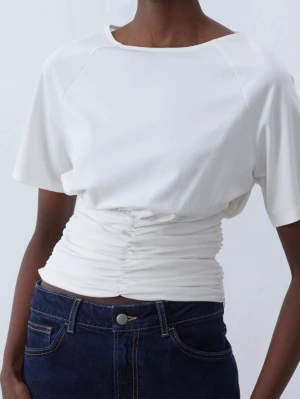 Vit croppad topp med rynkdetalj - Säljer en vit croppad topp med rynkade detaljer i midjan och korta ärmar. Sällan använd så väldigt bra skick! 