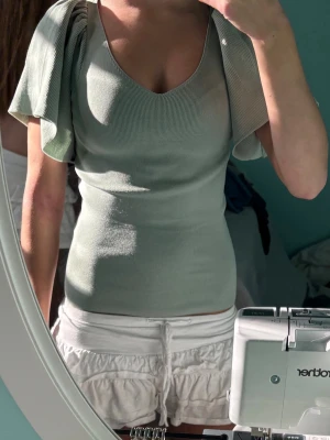 Ljusgrön ribbad topp med puffärm - Snygg ljusgrön ribbad topp från H&M med v-ringning och stora puffärmar. Materialet är mjukt och stretchigt, perfekt för dig som gillar en trendig och bekväm stil. Toppen har en croppad passform och är riktigt fin till både jeans och kjol.