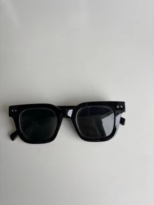 Svarta rektangulära solglasögon - Snygga svarta solglasögon med rektangulära bågar och mörka glas. Klassisk och stilren design som passar till de flesta outfits. Perfekta för soliga dagar och ger en cool vibe.