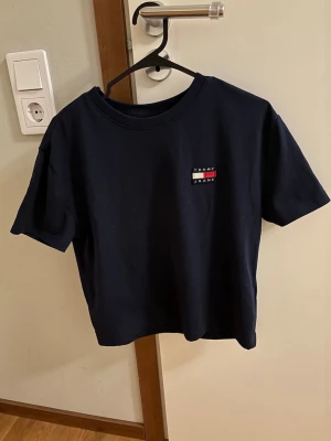 Mörkblå Tommy Jeans t-shirt - Snygg mörkblå t-shirt från Tommy Jeans med klassisk logga i vitt, rött och blått på bröstet. T-shirten har rund halsringning och korta ärmar. Tillverkad i mjukt bomullstyg för en bekväm känsla. Endast använd någon enstaka gång. I storlek XS💞