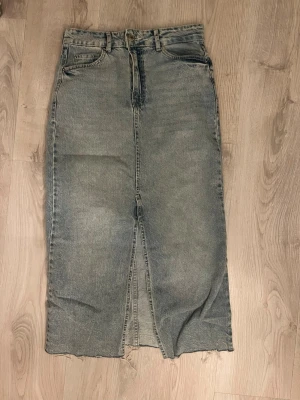 Lång jeanskjol med slits från Bershka - Säljer en snygg lång jeanskjol från Bershka i klassisk blå denim. 