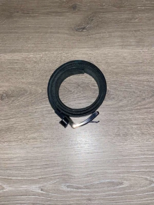 Svart klassiskt skärp i skinn av Gucci  - Säljer ett stilrent svart bälte i skinn med enkel metallspänne. Perfekt till jeans eller byxor för en clean look. Bältet har en klassisk design utan mönster och passar till många olika stilar.