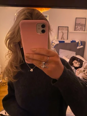 Mörkgrå stickad tröja - Mysig mörkgrå stickad tröja med rund hals och långa ärmar. Tröjan har en avslappnad passform och ribbstickade muddar vid ärmslut och nederkant. Perfekt för kalla dagar och enkel att matcha med jeans eller kjol.