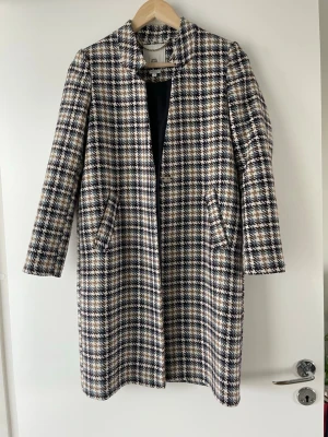 Petite kappa från River Island - Stilren rutig kappa från Zara i ullmix med svart, vit, beige och brun färg. Rak passform, diskret krage och två snedställda fickor framtill. Perfekt för petite tjejer 🥰 passade bra på mig som är 159 cm, ärmarna var perfekta! Säljer för att den inte längre kommit till användning 😇