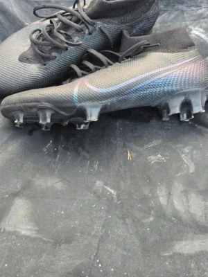 Nike Mercurial Superfly fotbollsskor - Snygga Nike Mercurial Superfly fotbollsskor i svart med subtila färgskiftningar och klassisk Nike Swoosh på sidan. Skorna har strumpliknande skaft och är tillverkade i ett lätt, syntetiskt material för bästa bollkontroll och grepp på planen. Perfekta för dig som vill ha stil och prestanda. PRIS KAN DISKUTERAS! Kommer även med en boll som du kan välja om du vill jag ska pumpa ena kostar det 10kr extra för behöver åka någonstans.