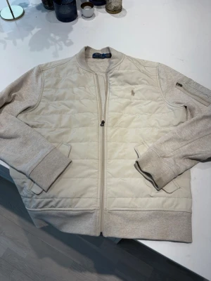 Cardigan från Polo Ralph Lauren - Snygg beige cardigan från Polo Ralph. Jackan har diskreta fickor och en liten logga på bröstet. Perfekt för dig som behöver ny fräsch vardagskacka till våren. Pris kan självklart diskuteras!