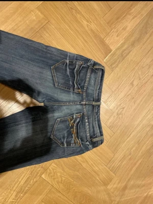 Snygga speciella bootcut jeans - Säljer ett par mörkblå jeans från Amisu storlek 26, lite slitningar där nere, en liten fläck som man knappt ser kolla bild 4, dragkedjan är trasig men går enkelt att fixa! 