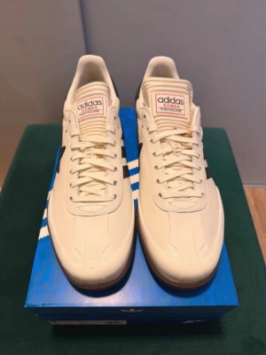 Adidas x BAPE Samba sneakers beige - Snygga Adidas Samba sneakers i samarbete med BAPE. Skorna är beige med mörkgrön stjärndetalj på sidan och klassiska Adidas-ränder. Ovandelen är i läder och sulan är gummifärgad. .