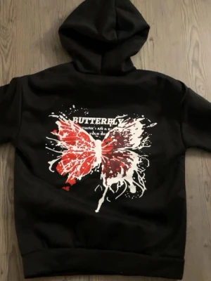 Svart hoodie med fjärilstryck - Mysig hoodie med stor huva och dragsnören. Super coolt tryck på ryggen och helt oanvänd 💓