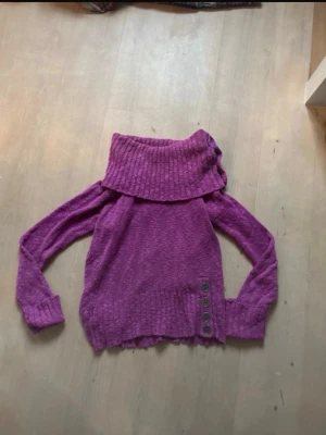 Turtleneck - Stickad turtleneck mörkare lila med knapp detaljer.jätte fint skick utöver att det finns ett hål i ärmen. Syns inte om man kavlar upp ärmarna som på de första två bilderna. Strl xl men mer som m