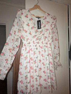 Blommig klänning från Boohoo - Söt blommig klänning från Boohoo. Klänningen har  volangdetaljer och v-ringad hals. Den är helt ny. Perfekt för sommarens alla tillfällen! ☀️