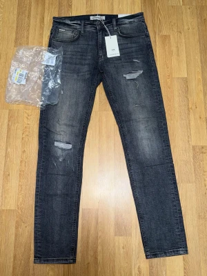 Svarta ripped jeans från Lindbergh - Snygga svarta jeans från Lindbergh med slitningar på låren och knäna. Modellen är slim fit med klassisk femficksdesign och normal midja. Jeansen har en tvättad look och är tillverkade i stretchigt denim för extra komfort.