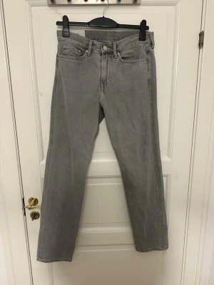 Gråa straight jeans från H&M - Säljer ett par gråa jeans från H&M med straight relaxed fit. Klassisk femficksmodell med raka ben och normal midja. Jeansen är tillverkade i bomull och har en enkel, stilren look som passar till det mesta. Perfekta för dig som gillar avslappnad stil. Storlek 29/32