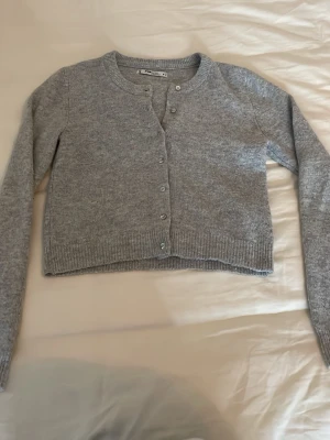 Grå kofta från new yorker i storlek s - Säljer en grå cropped kofta från new yorker med rund halsringning och långa ärmar. Koftan har ribbade muddar och knäpps med små knappar framtill. Perfekt att slänga över en topp för en chill look. Storlek s men sitter som en xs enligt mig! Säljer då den inte kommer till användning, köptes för 200kr! Mycket bra skick💕skriv för mer frågor eller prisförslag!💕