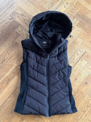 Svart dunväst med huva från Zara - Snygg svart dunväst från Zara, jätte fint skick men används inte längre, den är som ny, pris går jätte bra att diskuteras , vill egentligen bara bli av med den 