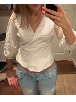 Vit omlottblus med trekvartsärm - Trendig vit omlott topp från Neo-Noir med trekvartsärm! 