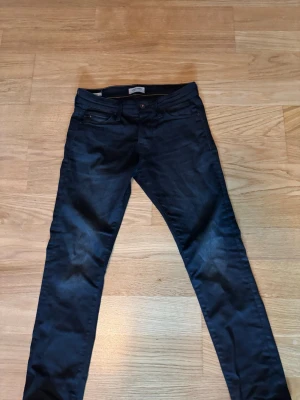 Mörkblå slim jeans från Jack & Jones - Snygga mörkblå slim fit jeans från Jack & Jones, modell Glenn. Klassisk femficksdesign, smal passform och diskreta sömmar. Perfekta för dig som gillar en modern och stilren look.