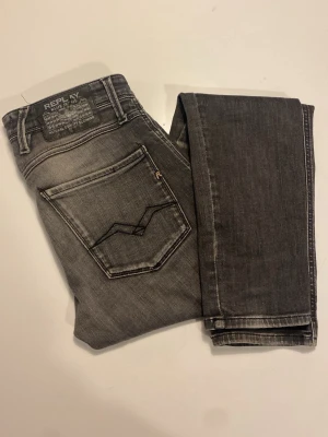 Grå Replay jeans  - Grå jeans från Replay med tvättad effekt och klassisk femficksmodell. Jeansen har raka ben och tydliga sömmar, samt detaljer på bakfickorna. Perfekta för dig som gillar en avslappnad men trendig stil.