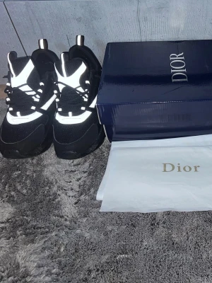 Svarta B22 skormed reflexdetaljer - Snygga svarta skor med vita och reflekterande detaljer. Skorna har en chunky sula och klassisk snörning. Materialet är en mix av mesh och mocka för en modern look. Kommer med originalkartong och dustbag.