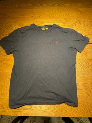 Mörkblå t-shirt från Polo Ralph Lauren - Säljer en mörkblå t-shirt från Polo Ralph Lauren med klassisk röd logga broderad på bröstet. Kan gå ner i pris vid snabb affär!!