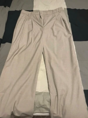 Kostymbyxor i begie färg - Väldigt fina kostymbyxor med vida ben.