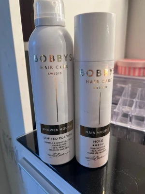 Bobbys Hair Care mousse duo - Två produkter från Bobbys Hair Care Sweden: en Shower Mousse Limited Edition och en Hair Mousse Hold. Båda är vita flaskor med gulddetaljer, 100% veganska och tillverkade i Sverige. Shower Mousse återfuktar och Hair Mousse ger volym och stadga.