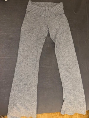 Grå ribbstickade leggings - Mysiga grå leggings med bred ribbstickad midja och lätt utsvängda ben. Tillverkade i mjukt stickat material som känns skönt mot huden. Perfekta för dig som gillar en avslappnad och trendig stil. Vikbar vid midjan och kortmidjade💗lappen på byxorna är klippt där bak!