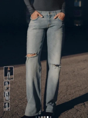 Blåa slitna jeans med femficksdesign - Ett par klassiska blå jeans med femficksdesign och slitna detaljer runt fickorna. Jeansen har en vintage look med ljus tvätt och synliga sömmar. Perfekt för dig som gillar en avslappnad och trendig stil.