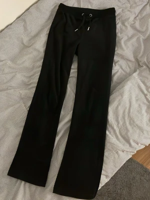 Svarta mjukisbyxor i velour - Säljer ett par svarta mjukisbyxor i mjuk velour med raka ben och dragsko i midjan. Byxorna har två bakfickor och bred resår i midjan för extra komfort. Perfekta för chill dagar eller när du vill vara extra bekväm.