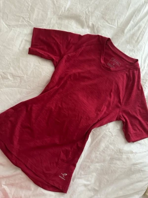 Röd tränings-tshirt  - Snygg röd tränings-tshirt med korta ärmar och rund hals. Tillverkad i ett lätt och snabbtorkande funktionsmaterial som passar perfekt till träning och sportaktiviteter. Diskret logga nere vid fållen.