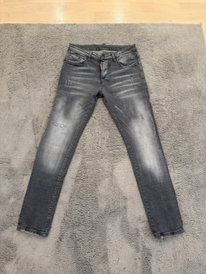 Dsquared  - Snygga grå jeans från dsquared med slitna detaljer och tvättad look. Klassisk femficksmodell med dragkedjegylf och Levi's röda logotagg vid fickan. Perfekta för en trendig och avslappnad stil.