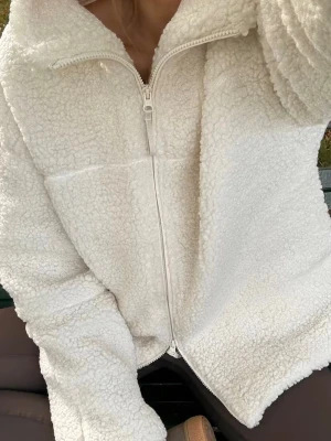 Vit teddyjacka med dragkedja - Mysig vit teddyjacka med hög krage och hel dragkedja framtill. Jackan har en oversized passform och är gjord i fluffigt pile-material som ger en riktigt skön och trendig look. Perfekt att slänga på sig när det är kyligt ute. Har prislapp kvar!! Vitt!!