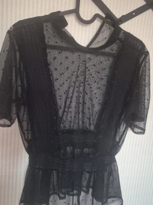 Svart transparent prickig klänning Gina Tricot - Säljer en svart transparent klänning från Gina Tricot i storlek XS. Klänningen har korta ärmar, resår i midjan och är dekorerad med små prickar i tyget. Perfekt för dig som gillar trendiga och unika plagg.