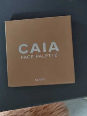CAIA Face Palette Classy Bronzer - Bronzer från CAIA i paletten Classy. Pudret har en varm, gyllene ton och kommer i en fyrkantig dosa med spegel. Perfekt för att skapa en solkysst look och definiera ansiktet. Paletten är stilren och lätt att ta med sig.