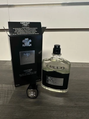 Creed Aventus Eau de Parfum 100ml - Creed Aventus Eau de Parfum i 100ml flaska. Flaskan är genomskinlig med svart och silver etikett och har en elegant, klassisk design. Kommer med original svart förpackning och lock med silverdetaljer. En ikonisk doft för dig som gillar exklusiva parfymer.