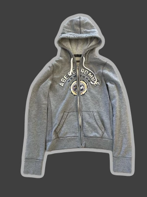Grå zip up hoodie från Abercrombie - Snygg grå zip up hoodie från Abercrombie. Perfekt för en avslappnad och lite Grisch/archive stil. Jag har använt den 3-4 gånger, skriv för mer bilder eller om du har frågor! Pris är diskuterbart 🤍!