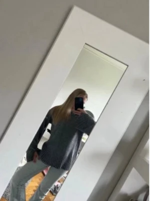 Grå oversized stickad tröja - Mysig grå stickad tröja med oversized passform och bred ribbstickning vid ärmslut och nederkant. Tröjan har rund halsringning och en dekorativ söm framtill. Perfekt för lager på lager och chill dagar.