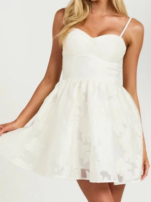 Vit kort klänning med tunna band. Showpoo  - Söt vit kortklänning med tunna axelband och hjärtformad urringning. Kjolen är lätt utställd och har ett subtilt blommönster i tyget. Perfekt för student och sommarens alla tillfällen. Säljer för att jag hittat en annan studentklänning, aldrig använd. Köpt för 700